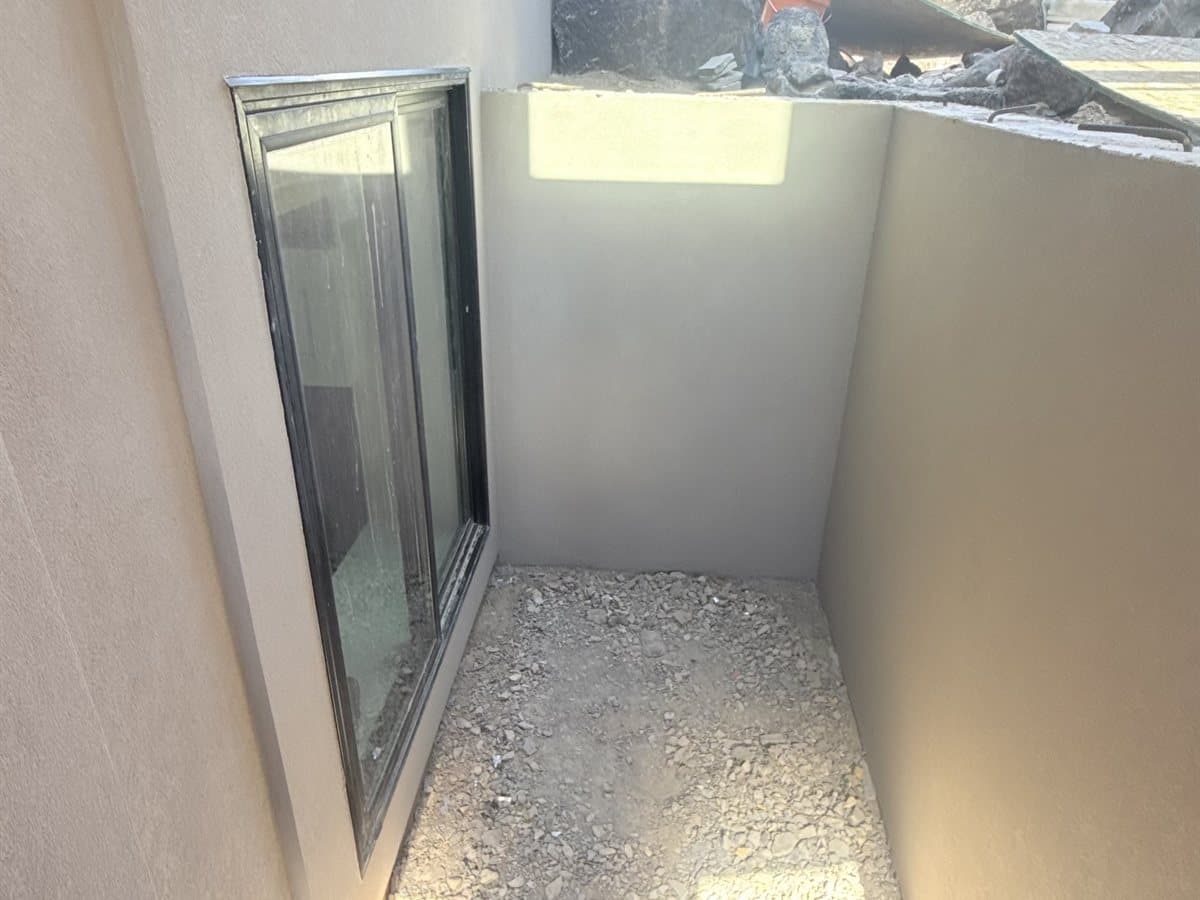Cream stucco finish lining a basement window well